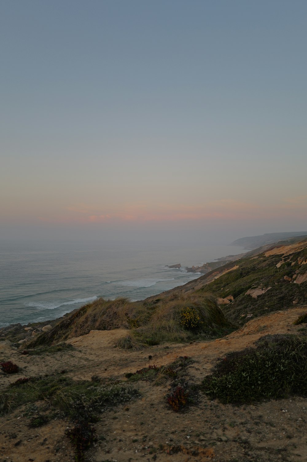 a bench sitting on top of a hill near the ocean