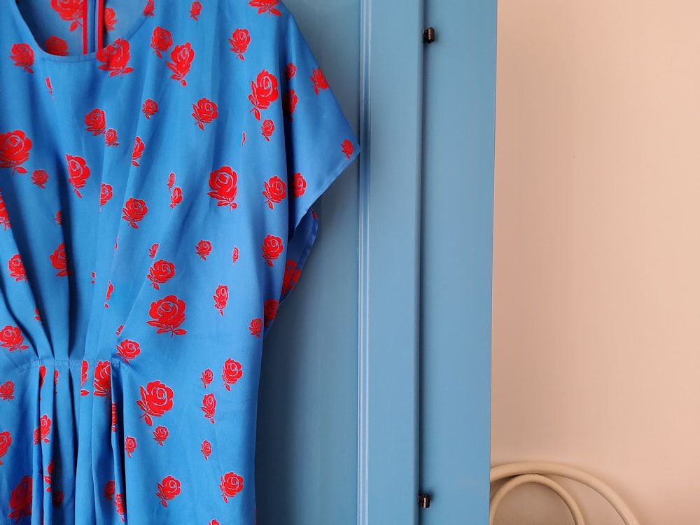 une robe bleue et rouge accrochée à une porte bleue