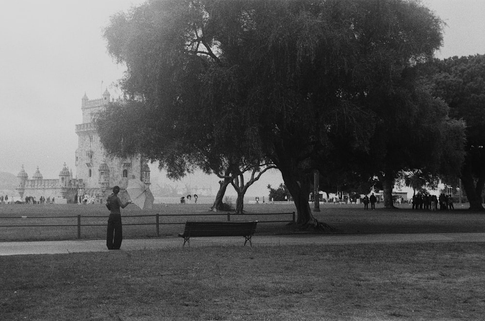 a black and white photo of a woman standing under a tree