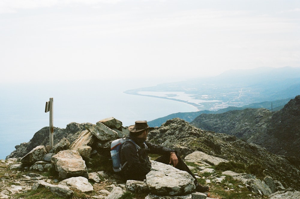 a man sitting on top of a mountain next to a flag