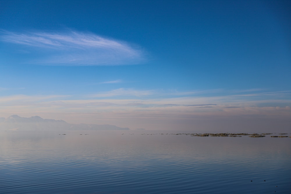 a large body of water sitting under a blue sky