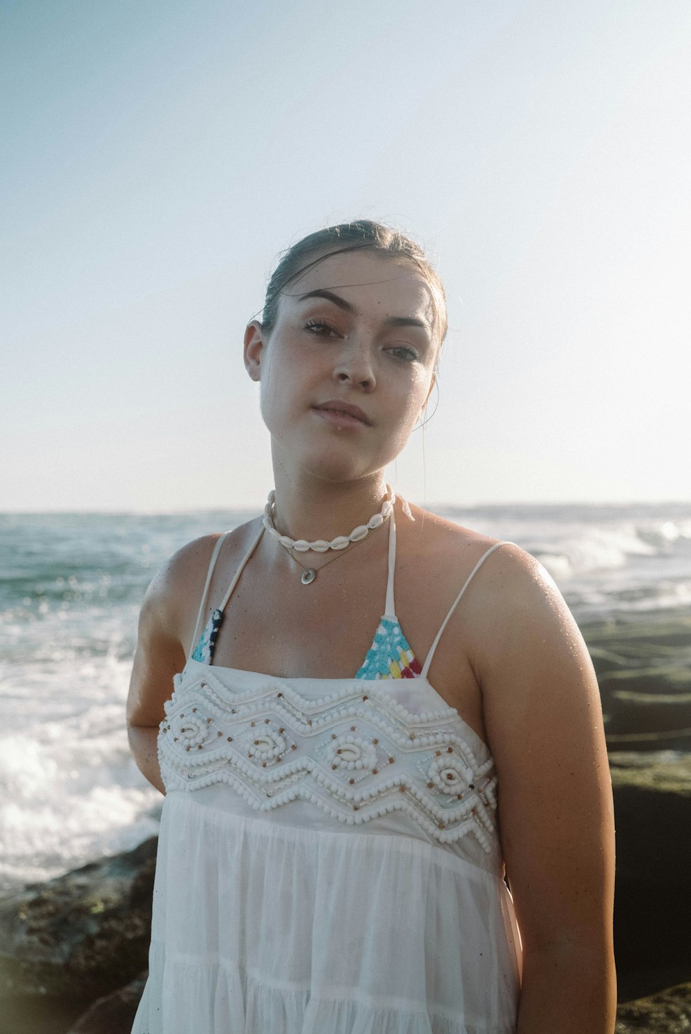 a woman in a white dress standing by the ocean