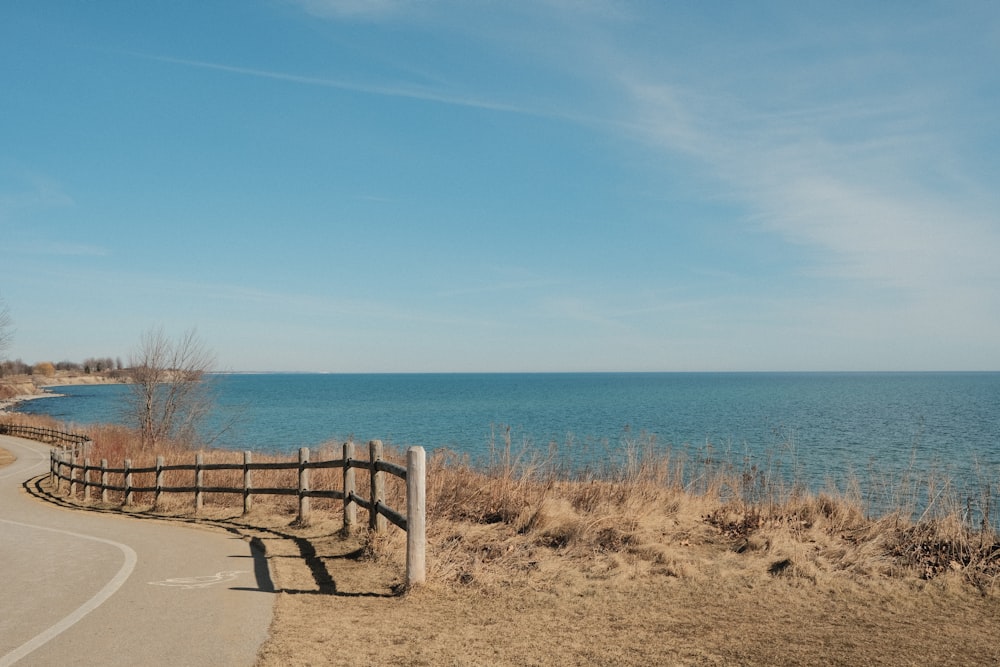 a wooden fence on the side of a road next to a body of water