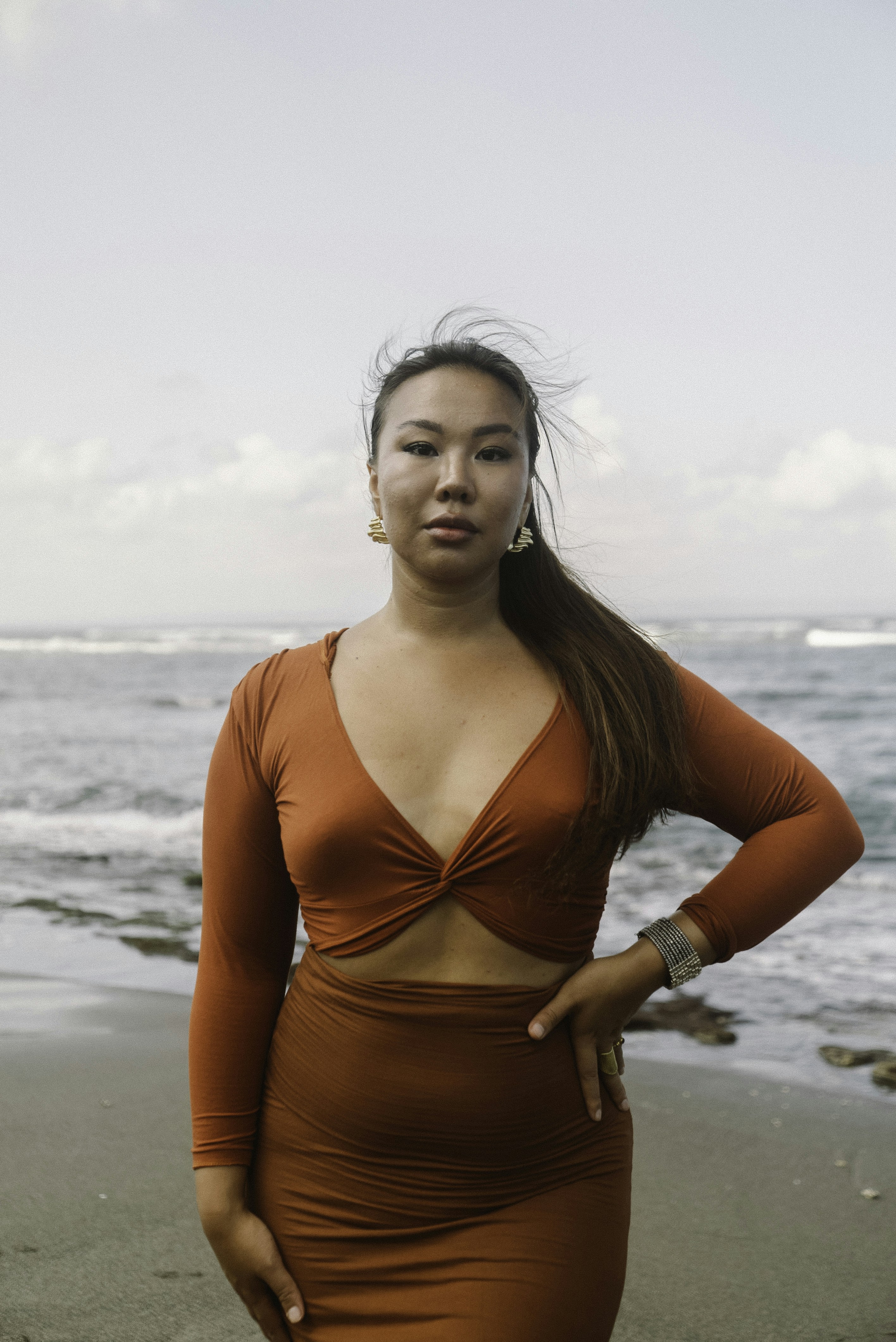uma mulher em pé em uma praia ao lado do oceano