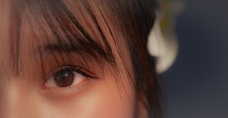 a close up of a person's eye with a flower in the background