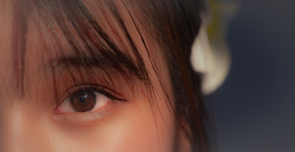 a close up of a person's eye with a flower in the background