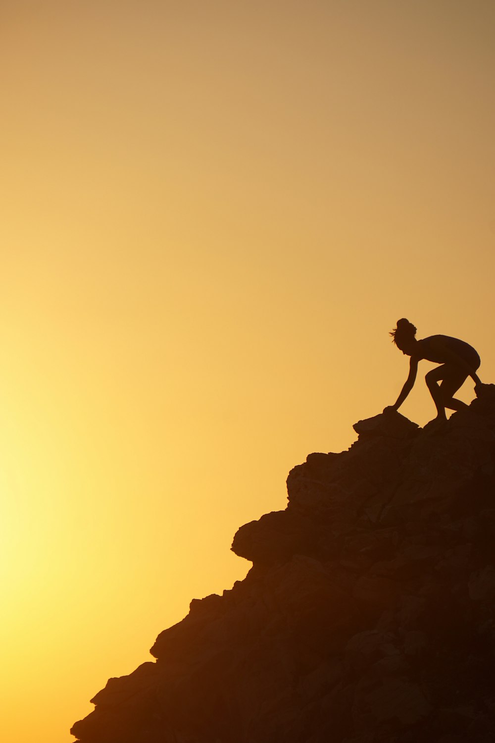 una persona che si arrampica sul fianco di una montagna al tramonto