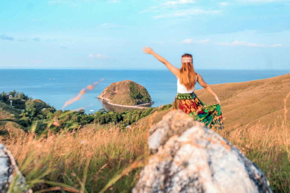 a woman standing on top of a lush green hillside