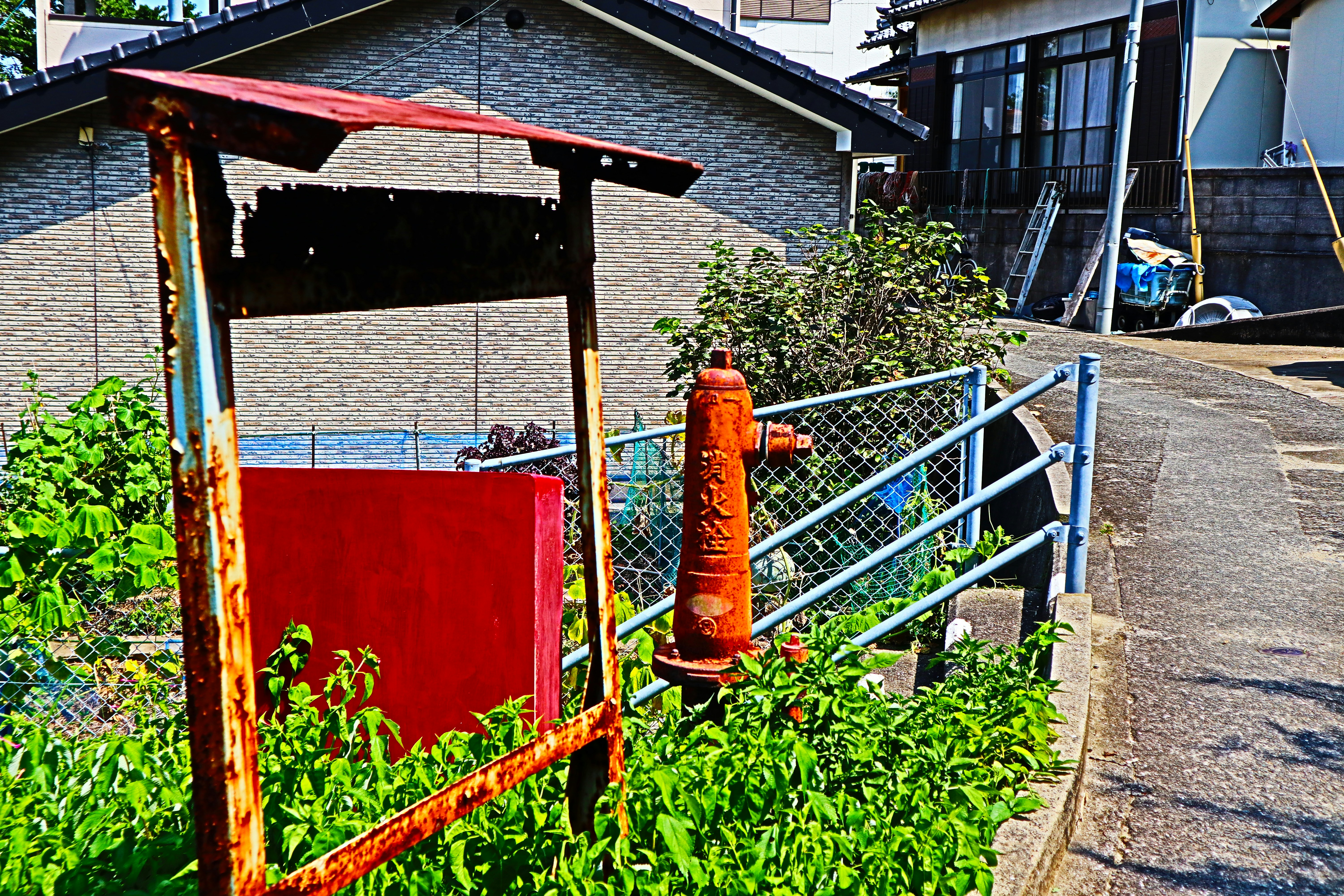 a red box sitting on the side of a road next to a fence