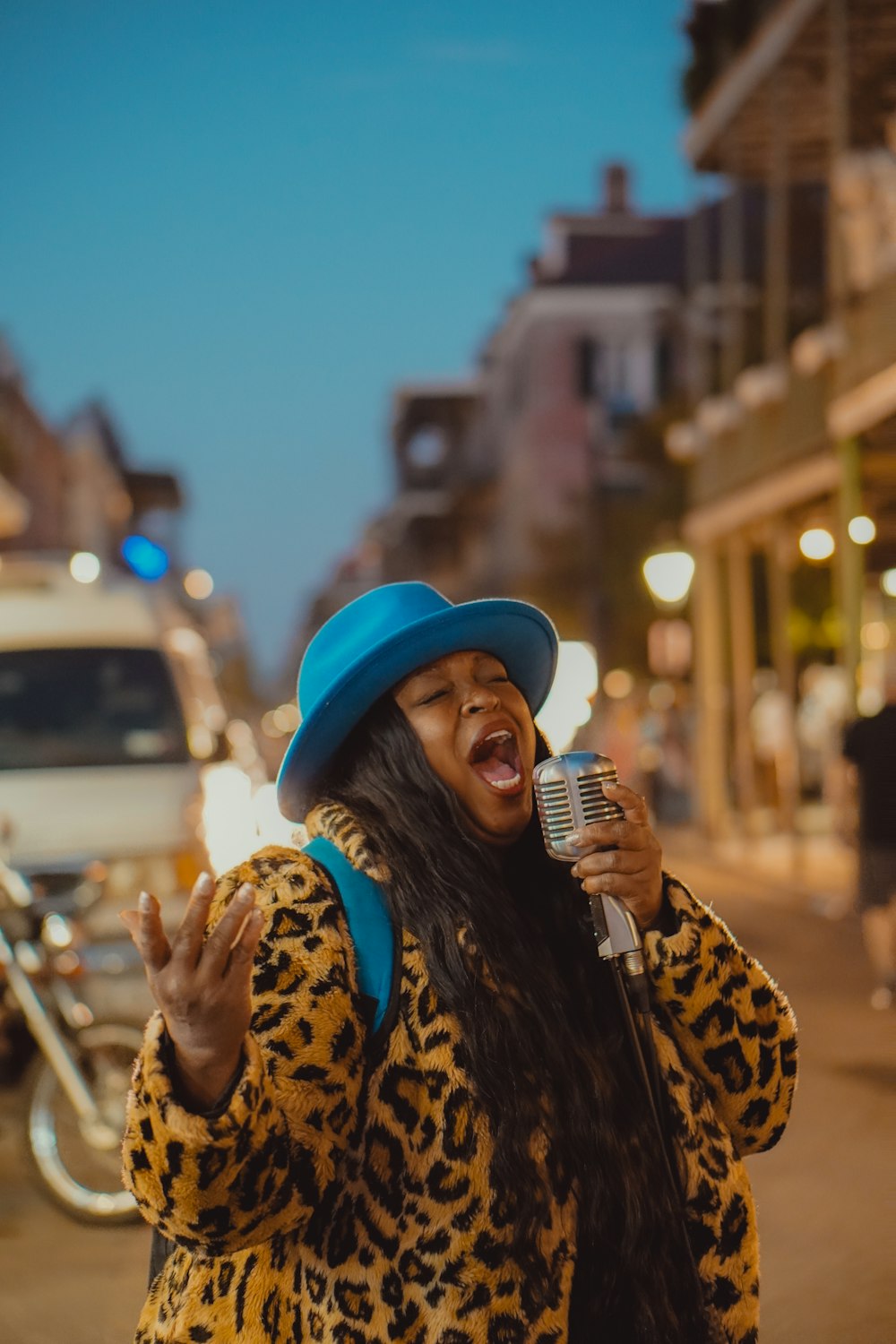 a woman singing into a microphone on a city street