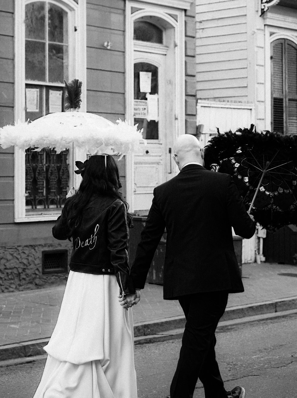 um homem e uma mulher caminhando por uma rua segurando um guarda-chuva