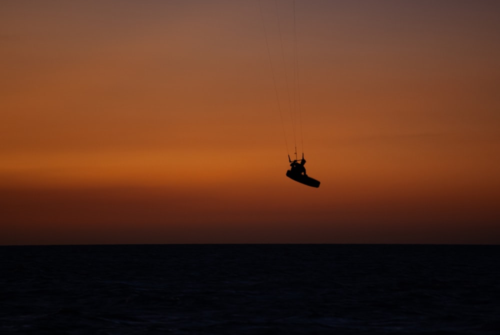 uma pessoa está parasailing no oceano ao pôr do sol