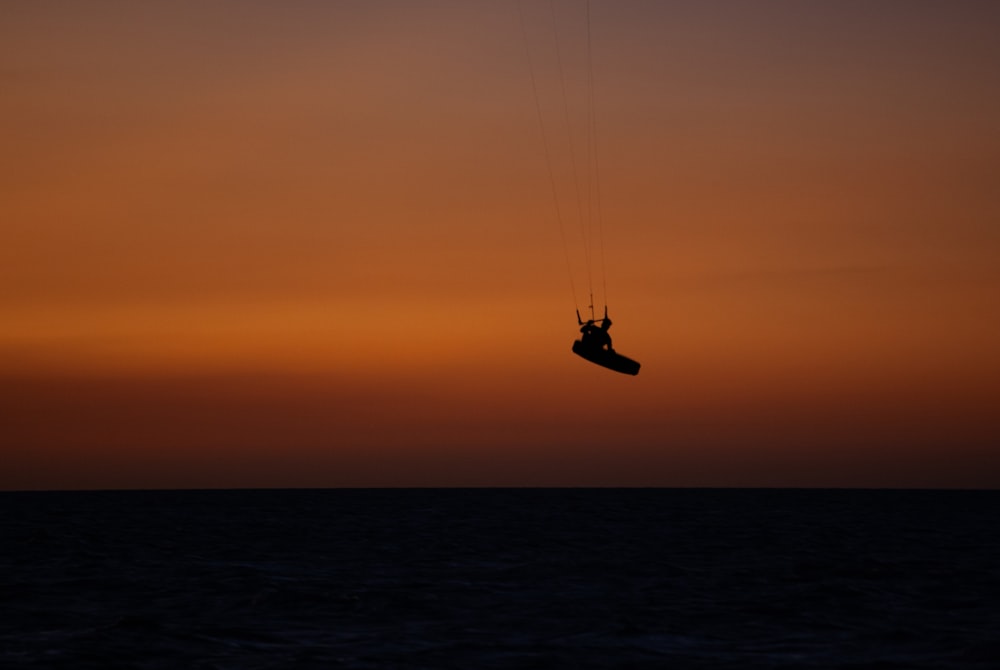 a person is parasailing in the ocean at sunset