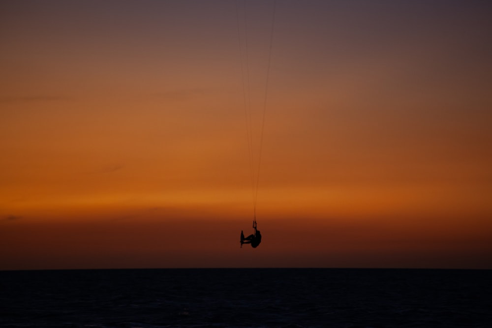 uma pessoa está parasailing no oceano ao pôr do sol