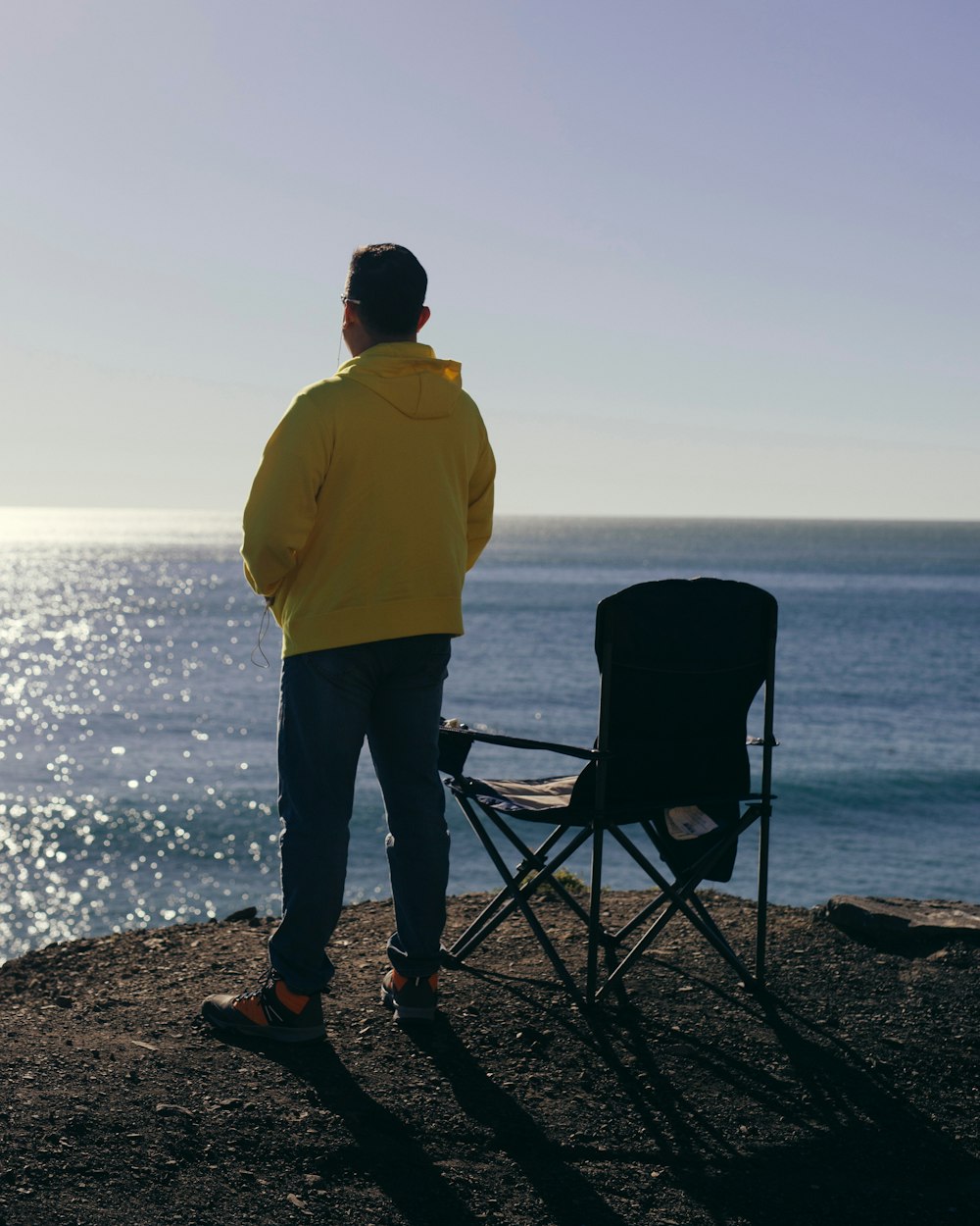 un uomo in piedi accanto a una sedia in cima a una spiaggia