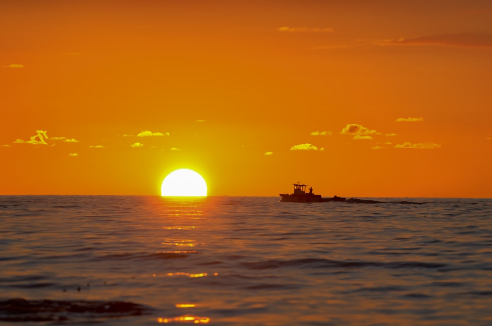 a small boat in the ocean at sunset