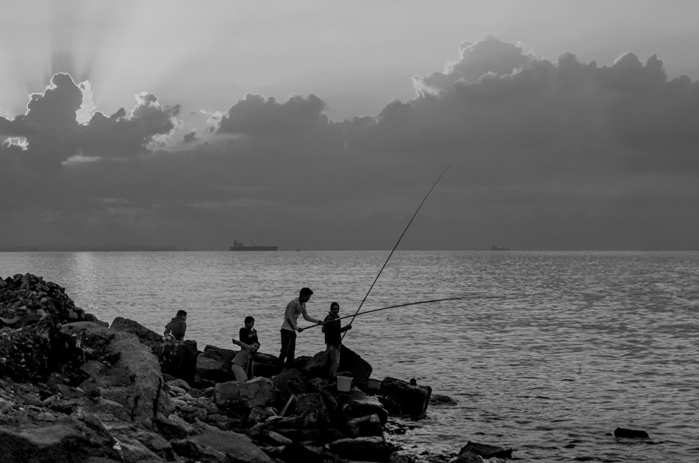 a group of people standing on top of a rocky shore