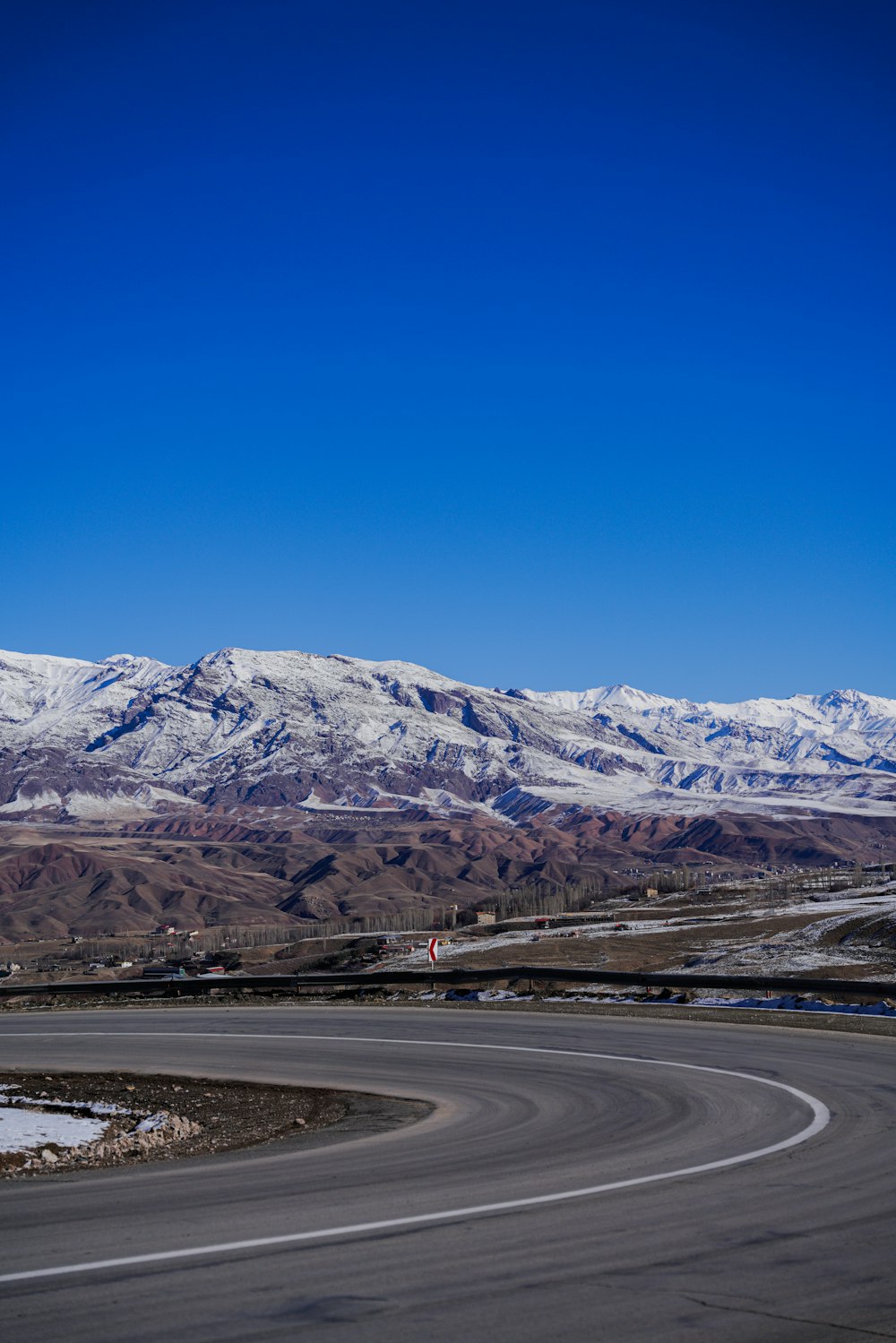 une route sinueuse avec des montagnes enneigées en arrière-plan