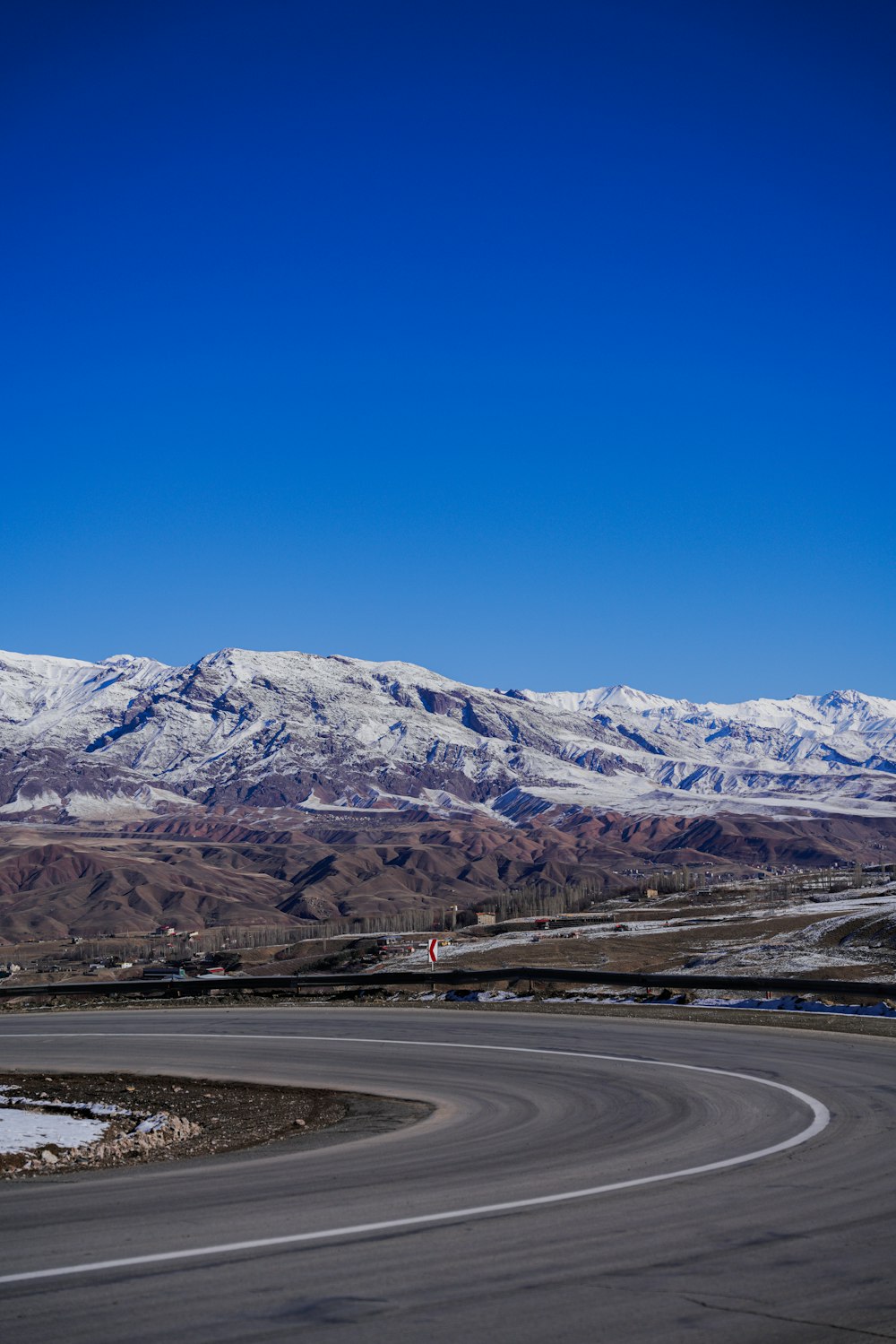 a curved road with snow covered mountains in the background