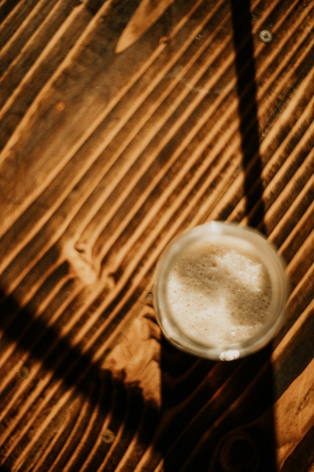 a glass of beer sitting on top of a wooden table