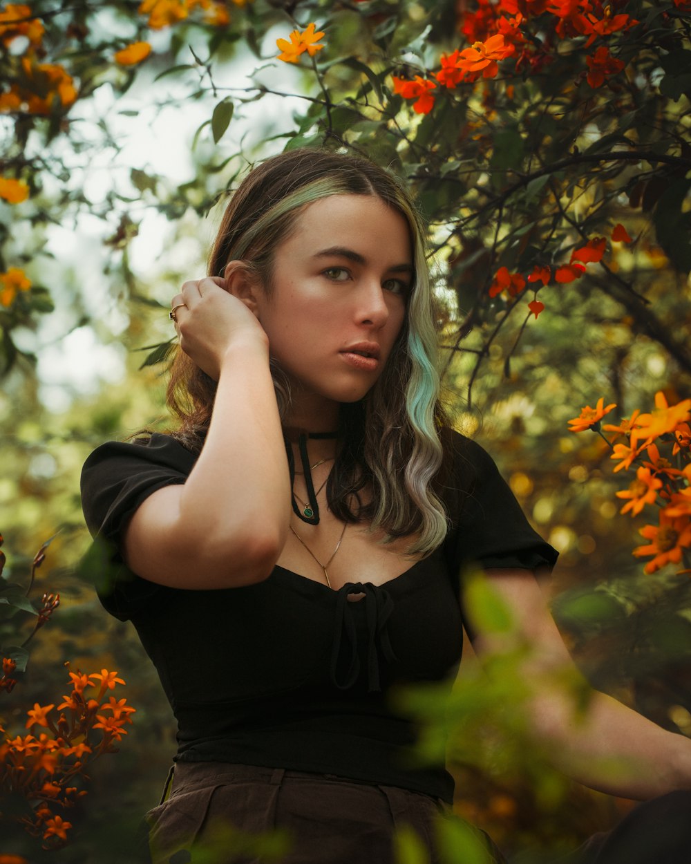 a woman standing in front of a tree with orange flowers