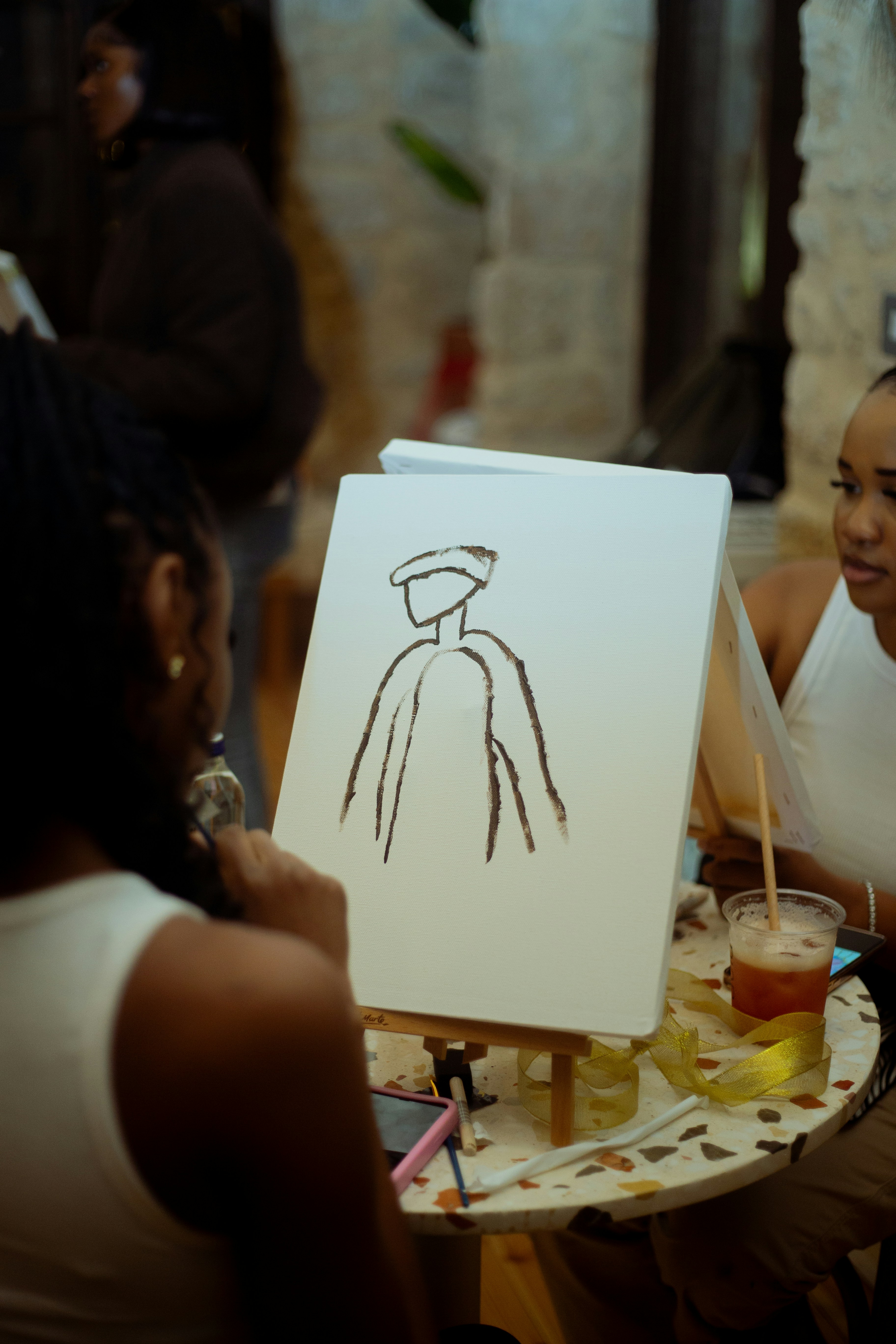 eine Frau sitzt an einem Tisch mit einer Zeichnung auf einer Staffelei