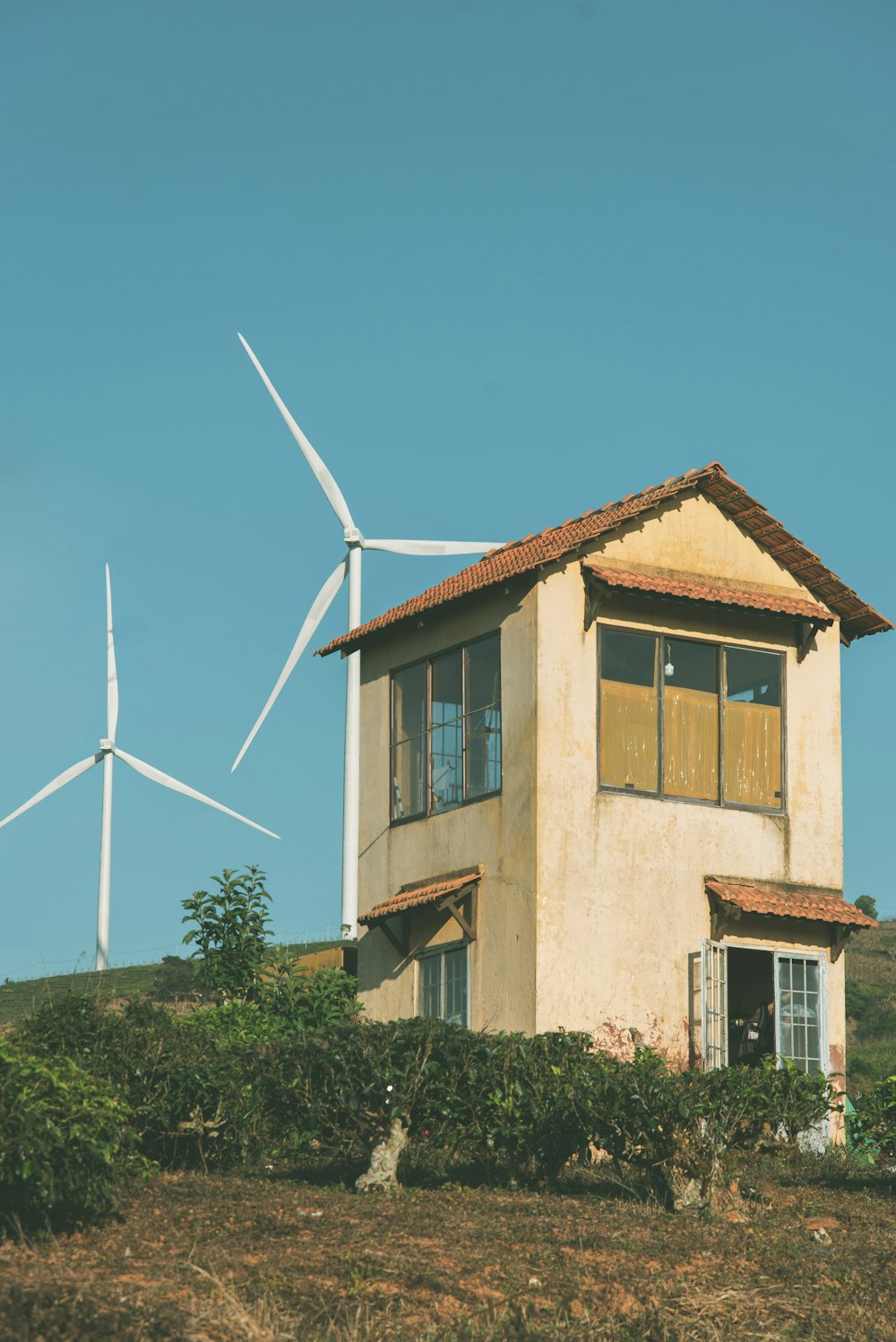 a house on a hill with wind turbines in the background