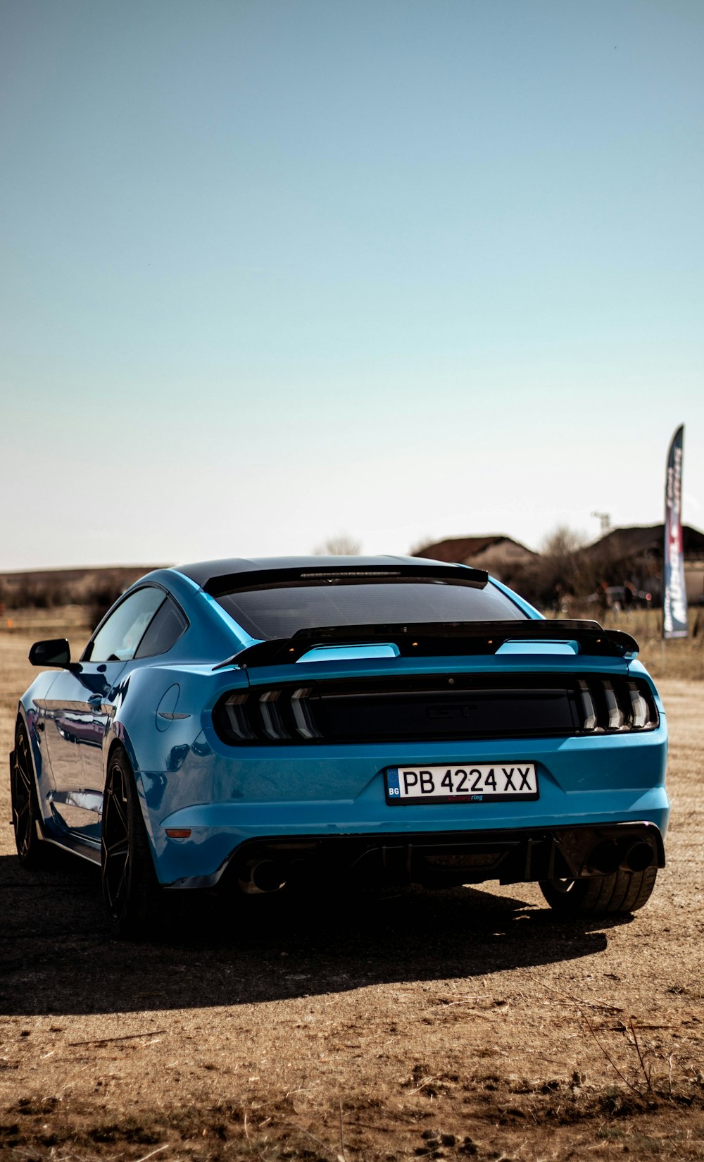 a blue sports car parked in a dirt field