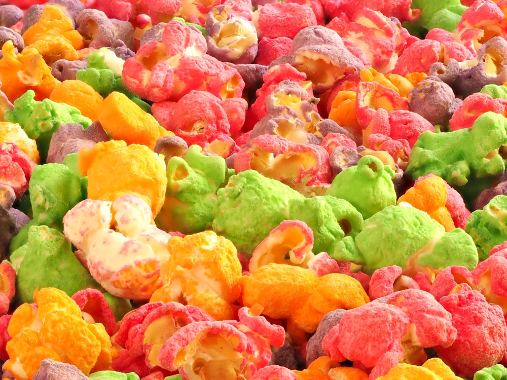 a pile of colorful popcorn with a teddy bear in the middle of it
