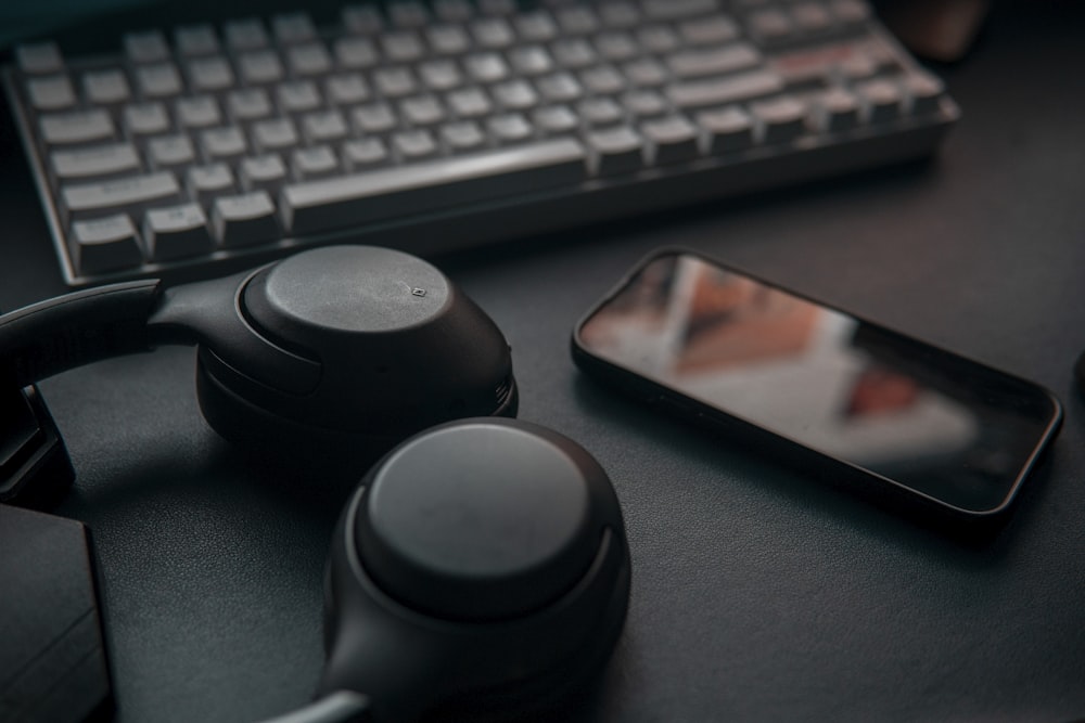 a cell phone sitting next to a keyboard and headphones