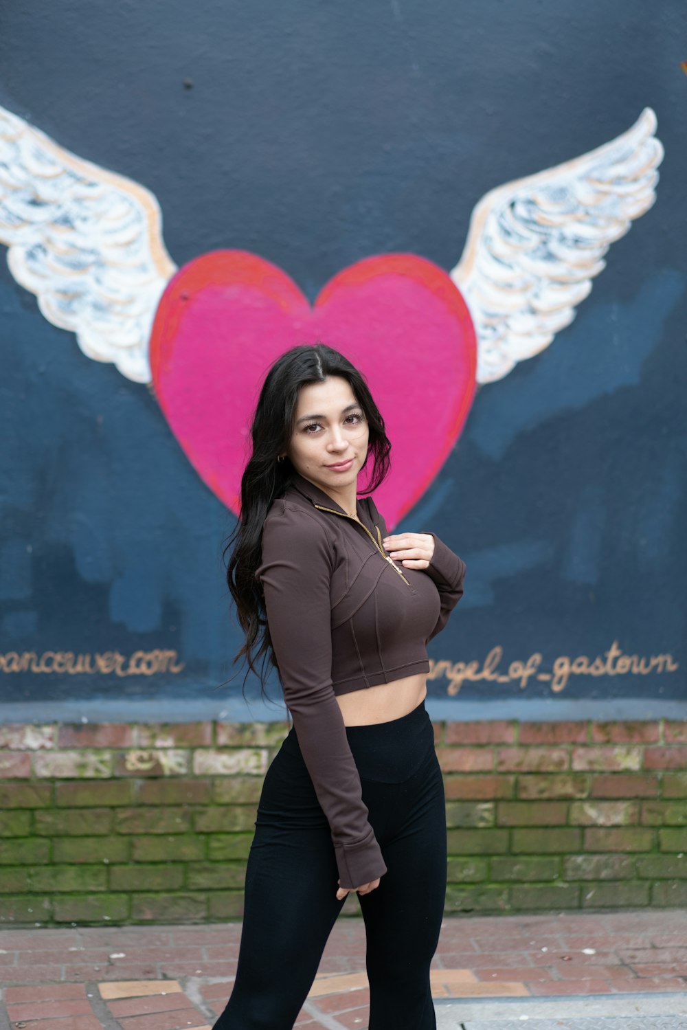 a woman standing in front of a wall with a heart painted on it