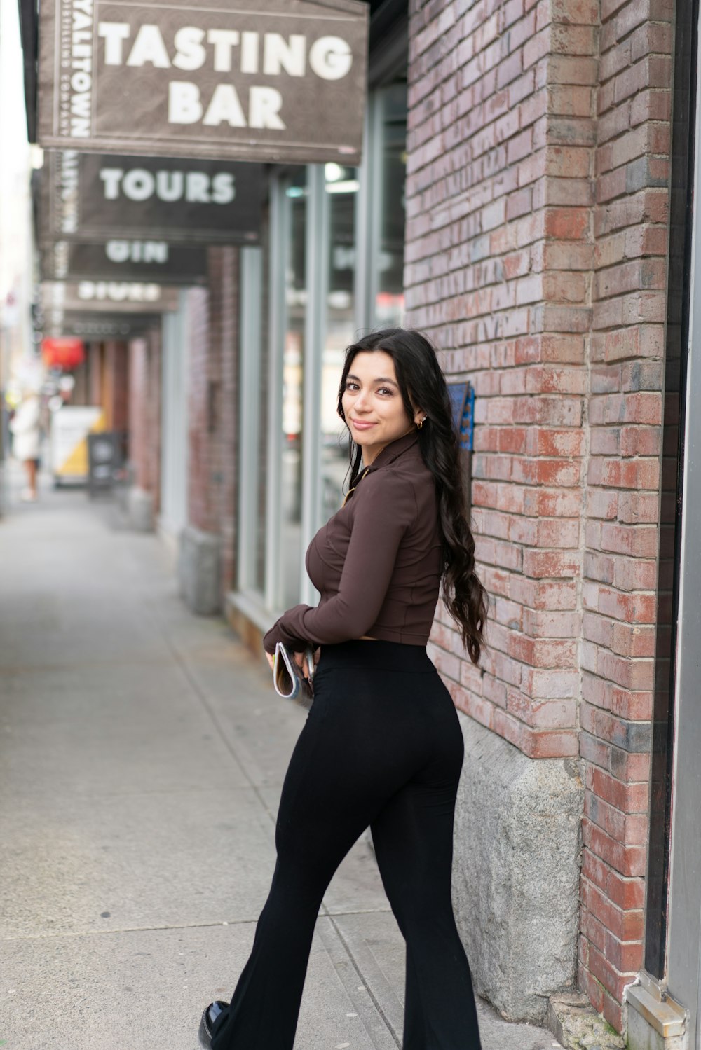 a woman standing on a sidewalk next to a brick building