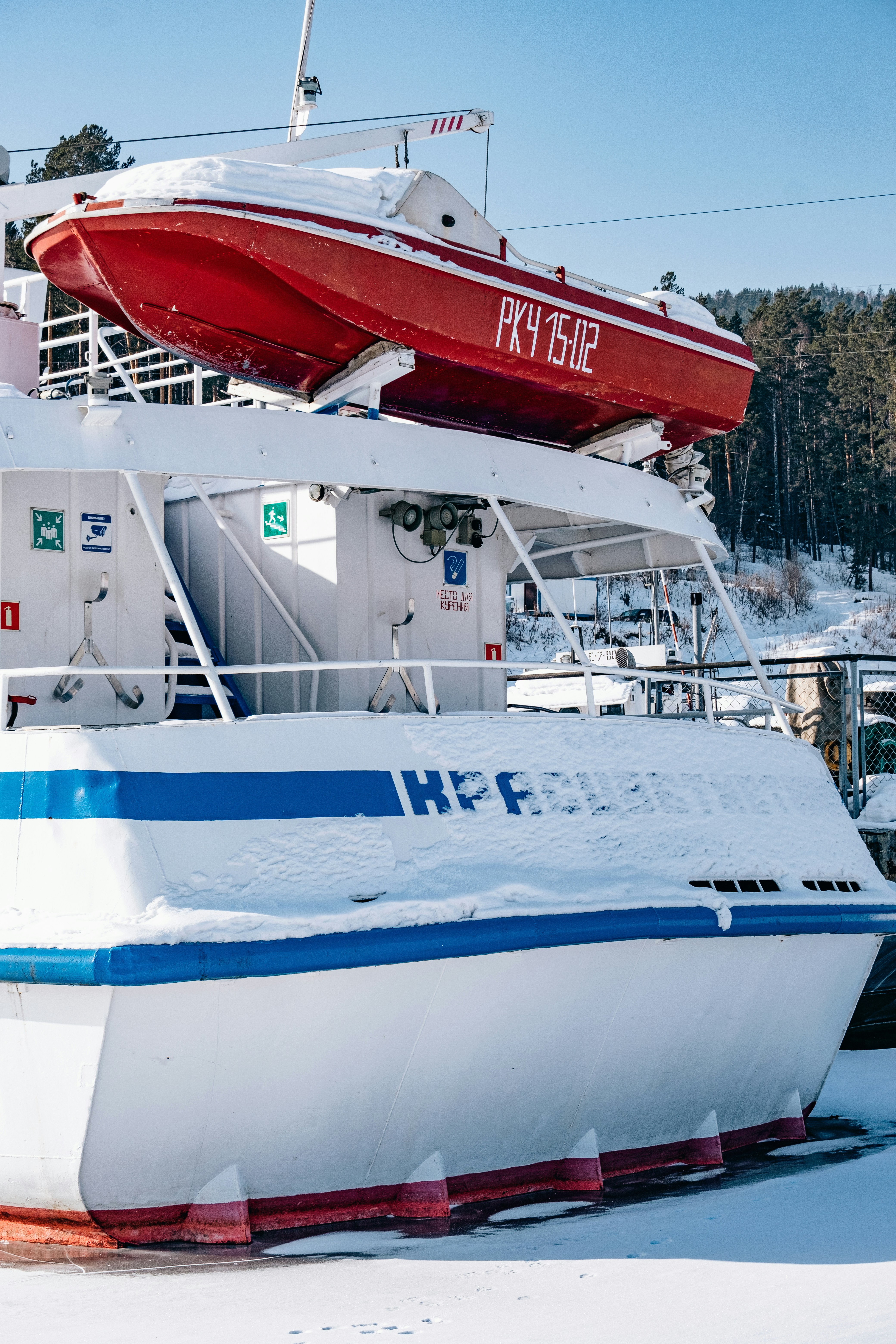 a red and white boat sitting on top of snow covered ground