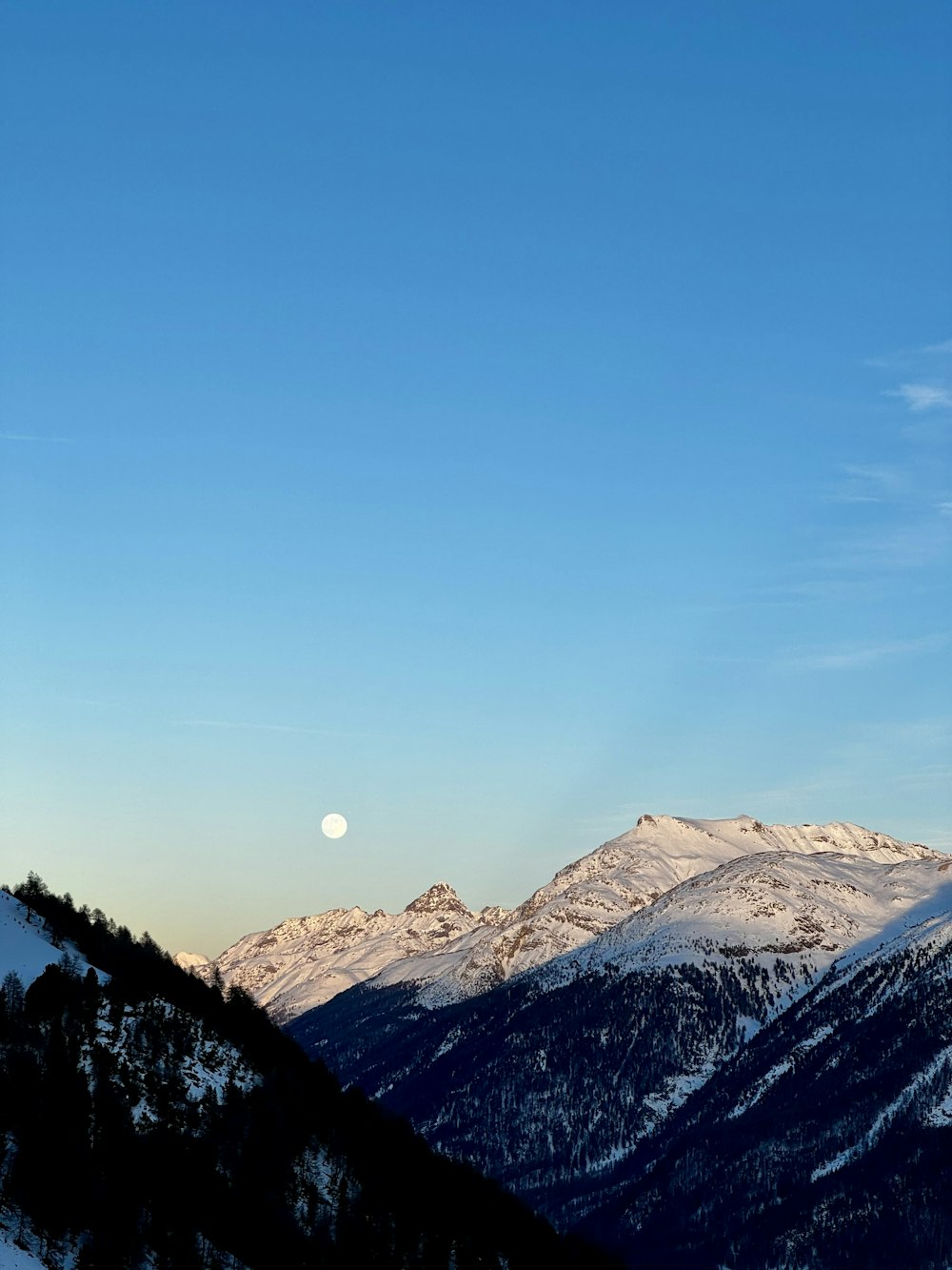 a view of a mountain range with a moon in the sky