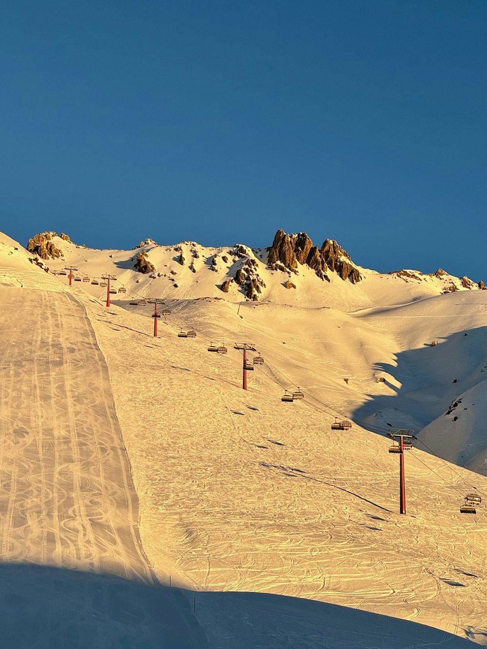 a snow covered ski slope with a ski lift in the distance