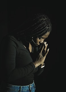 a woman in a black shirt is holding her hands together