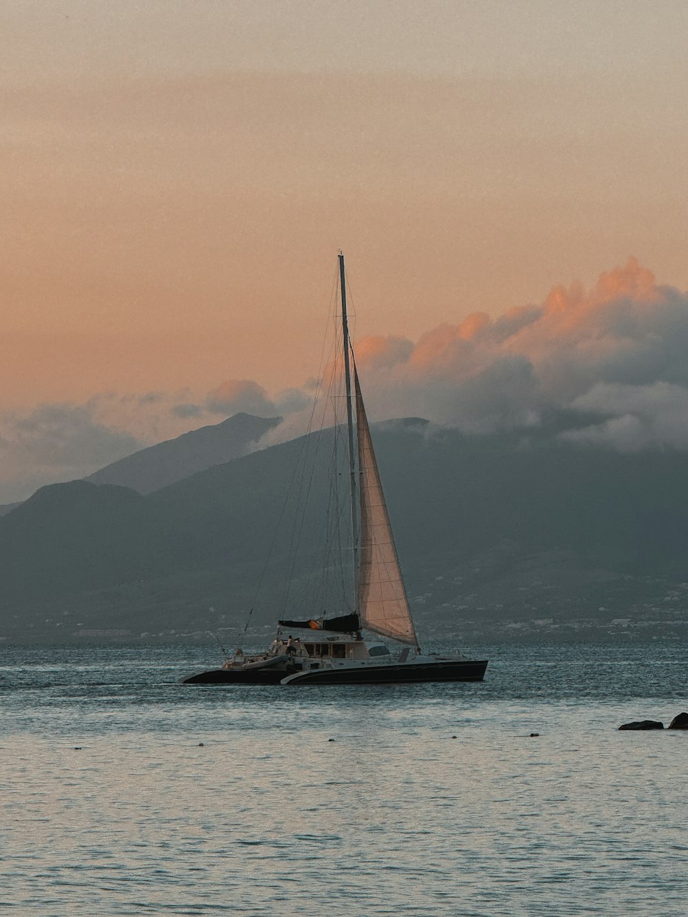 a sailboat in the water with a mountain in the background