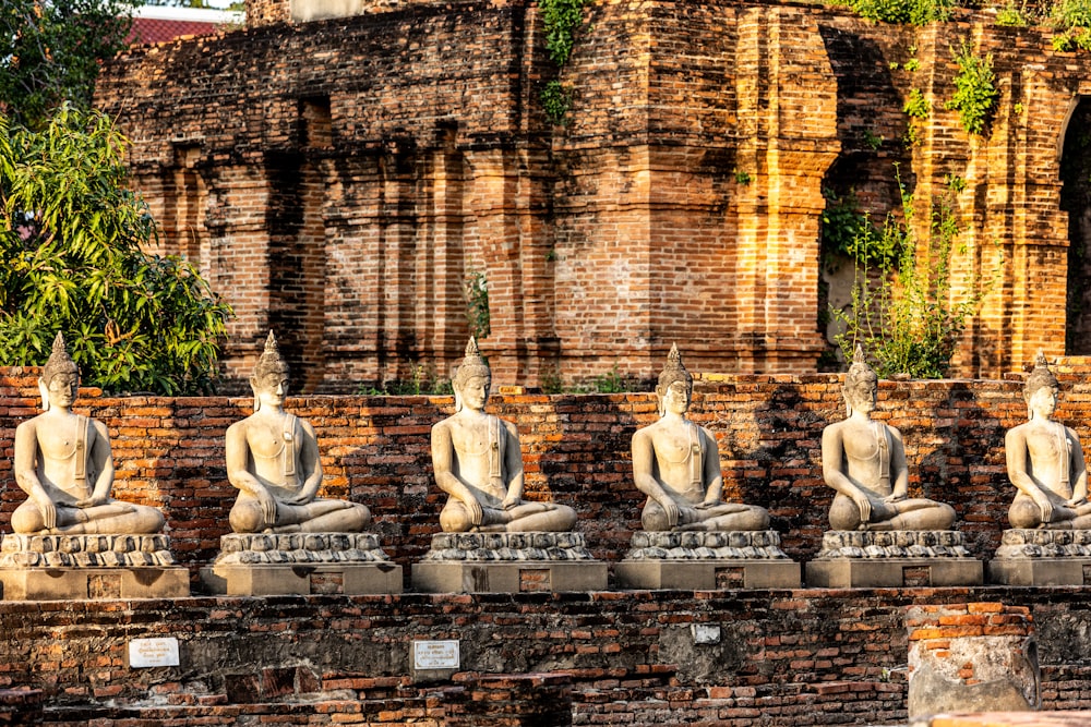 a row of buddha statues sitting on top of a stone wall