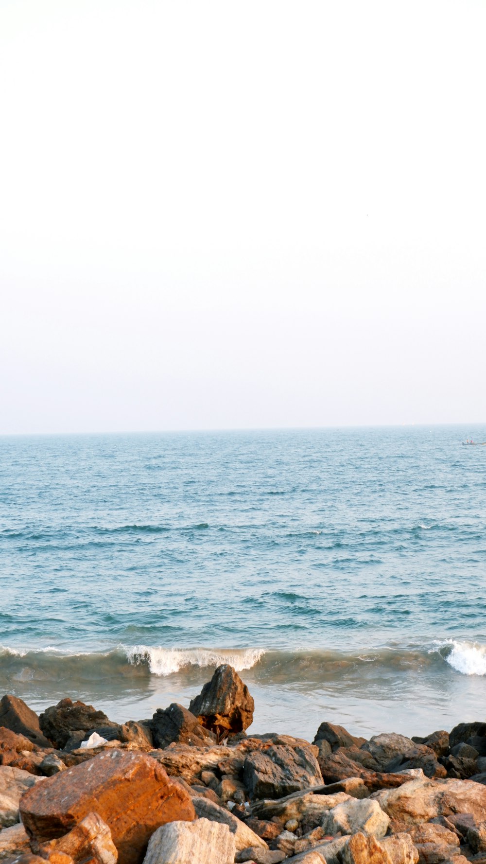 a person standing on a rocky beach next to the ocean