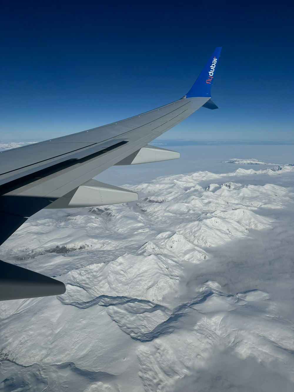 the wing of an airplane flying over a mountain range