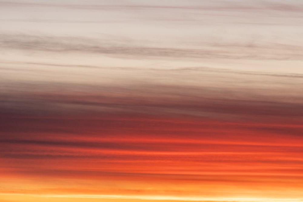 a plane flying in the sky at sunset