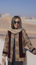 a woman wearing sunglasses and a scarf standing next to a wall