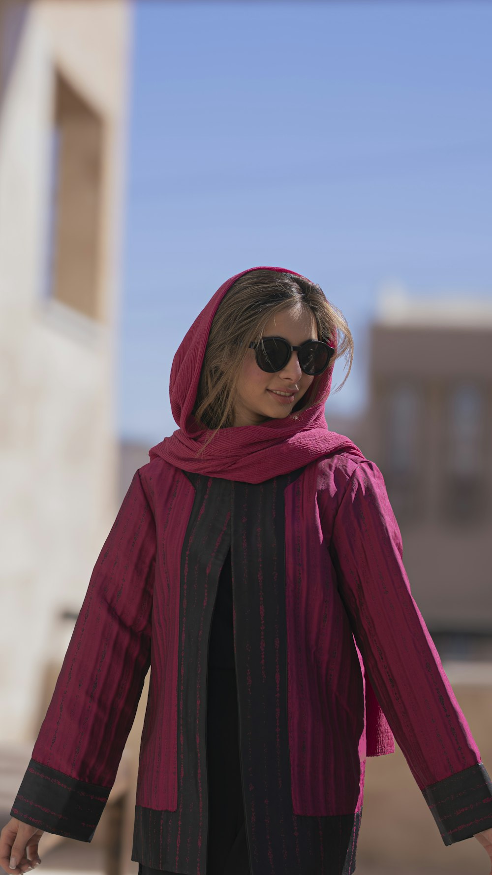 a woman wearing sunglasses and a pink scarf