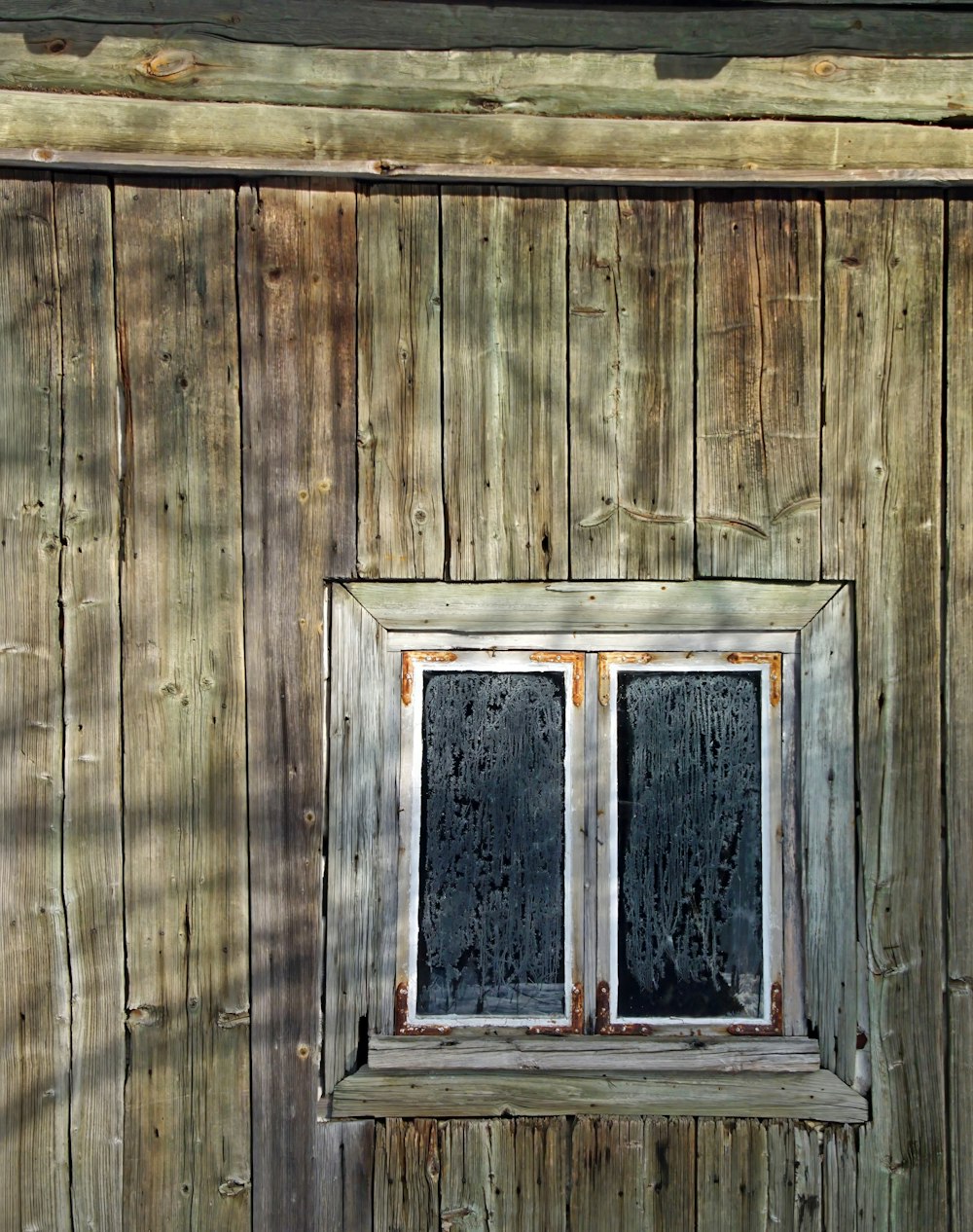 eine Holzwand mit einem Fenster und einer Bank davor