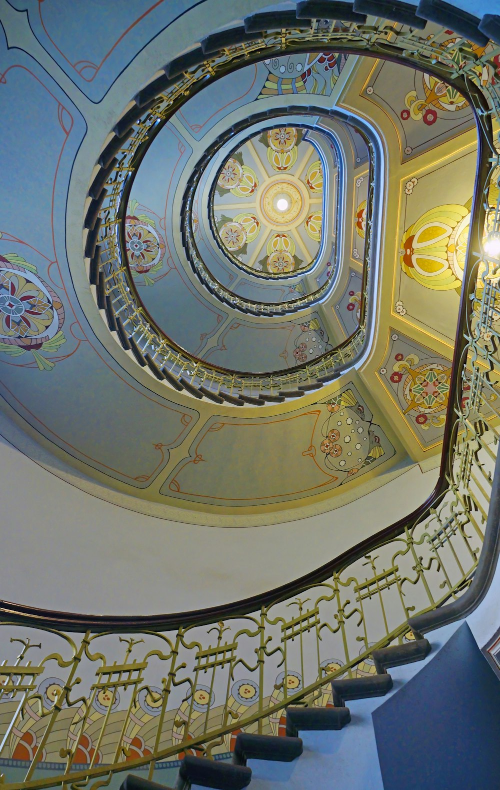 a spiral staircase with a chandelier in a building