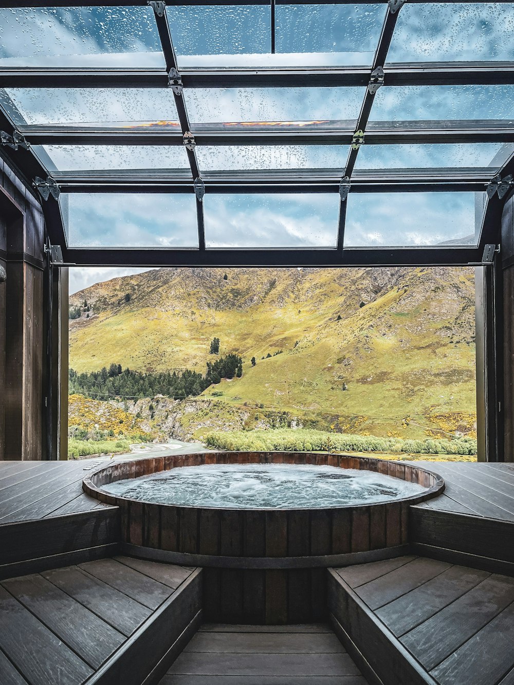 a hot tub in a room with a view of mountains