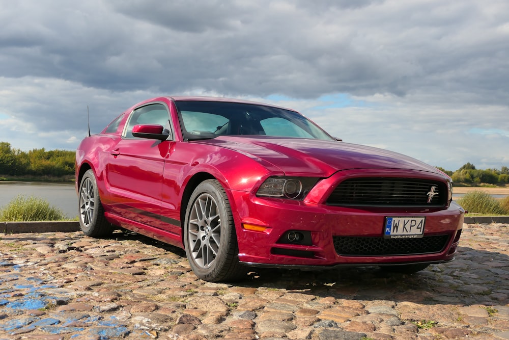 a red car parked on a cobblestone road