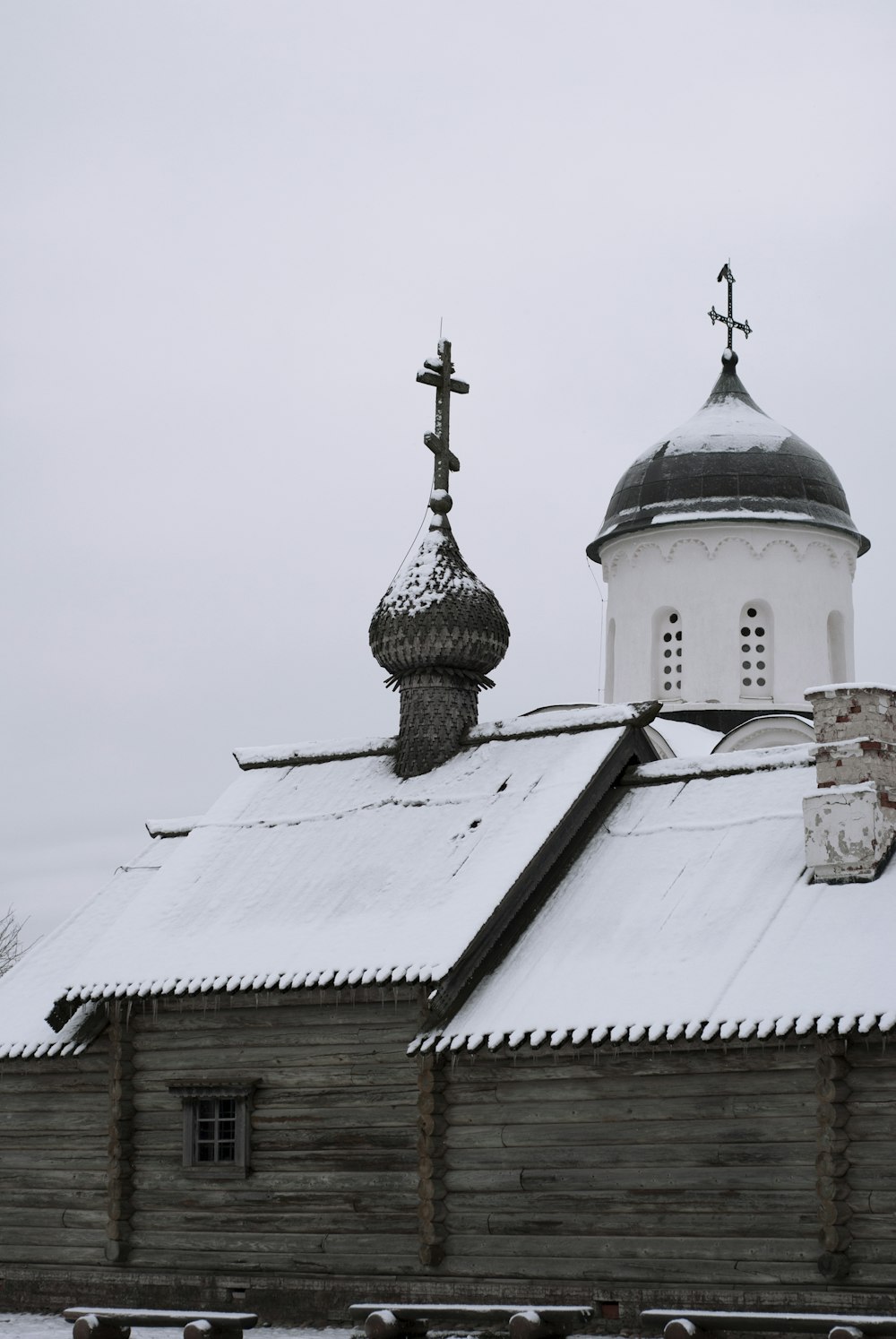 una iglesia blanca con un techo negro cubierto de nieve