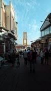 a group of people walking down a street next to tall buildings