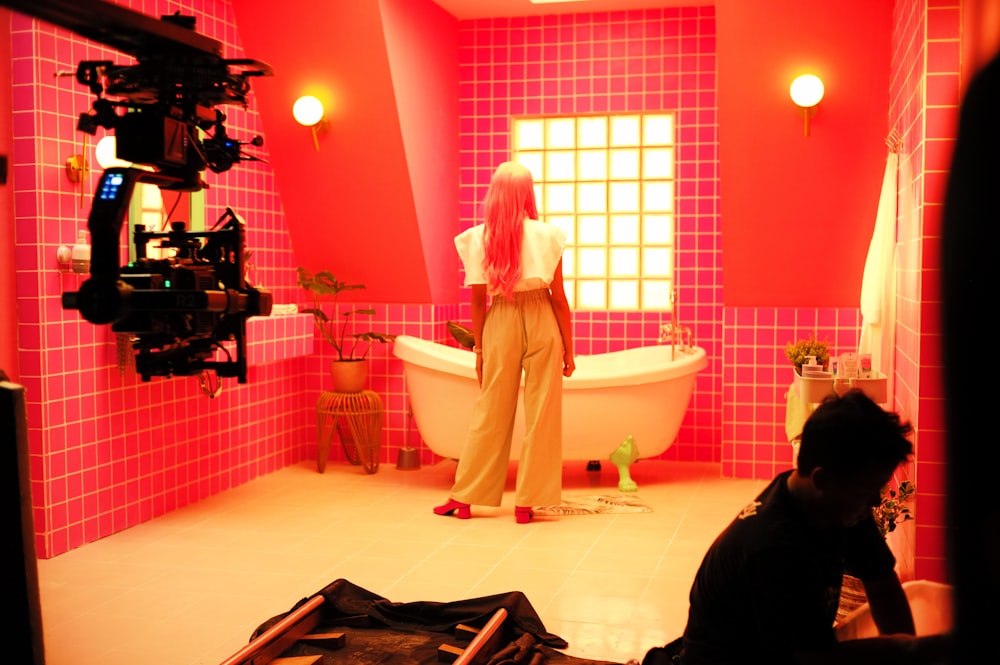 a woman standing in a bathroom next to a tub